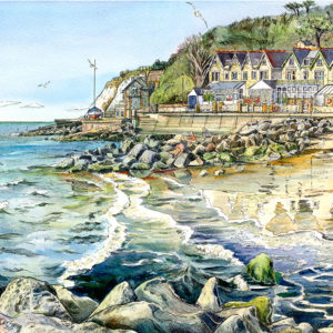 The view from the sea defence rocks at Bonchurch of a couple walking across the beach and a row of victorian properties on the front and their reflections on the Isle of Wight